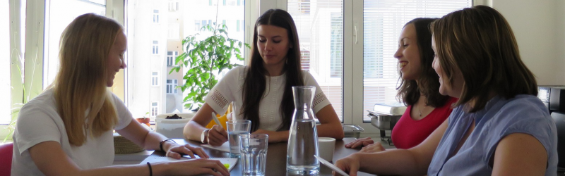 Interns stand around a table and talk about their experiences